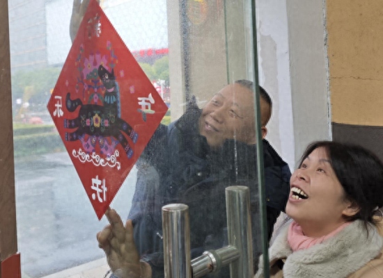 图为营销人员与零售客户一起张贴窗花，罗诗飏摄。